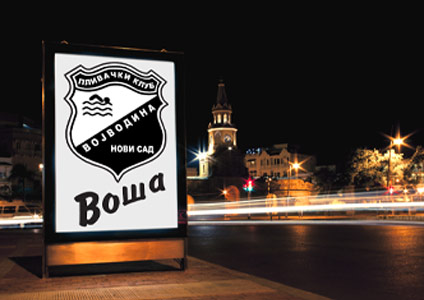 LED bilbord na trotoaru, noću, s reklamom za plivački klub Vojvodina.